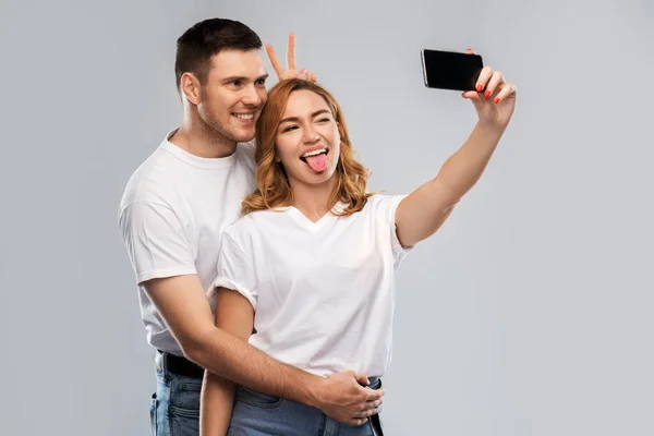 Gelukkig paar in wit t-shirts het nemen van selfie — Stockfoto
