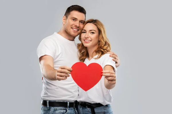 Sonriente pareja sosteniendo gran corazón rojo — Foto de Stock