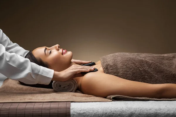 Hermosa mujer teniendo caliente piedra masaje en spa —  Fotos de Stock