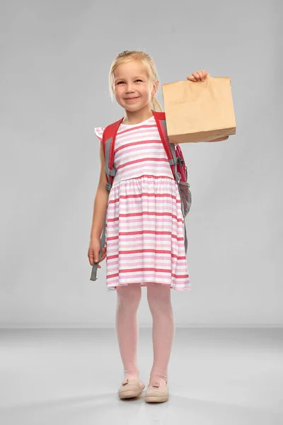 Маленькая студентка со школьным обедом в бумажном пакете — стоковое фото