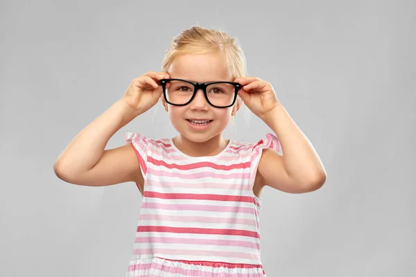 Usmívající se roztomilá holčička v černých brýlích — Stock fotografie