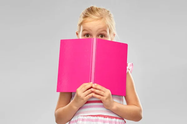 Menina se escondendo sobre livro — Fotografia de Stock