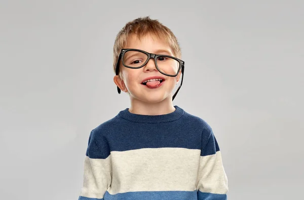 Porträtt av en liten pojke i glasögon som visar tungan — Stockfoto