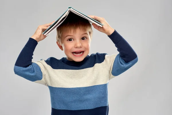 Petit garçon avec un toit de livre sur la tête — Photo