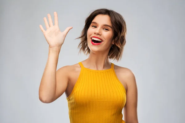 Glad leende ung kvinna viftande hand — Stockfoto