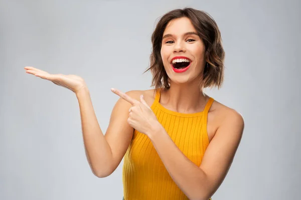 Glad ung kvinna håller något på tom hand — Stockfoto