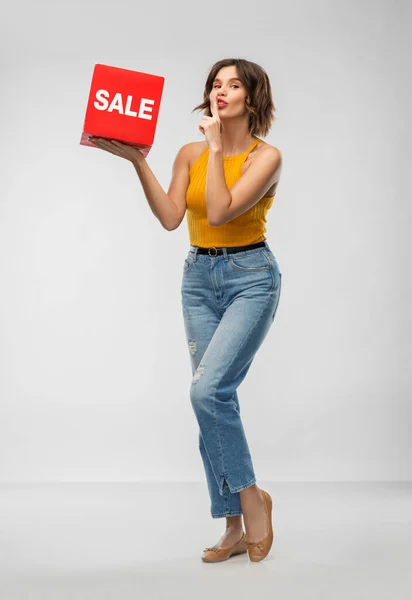 Glad leende ung kvinna poserar med försäljning tecken — Stockfoto