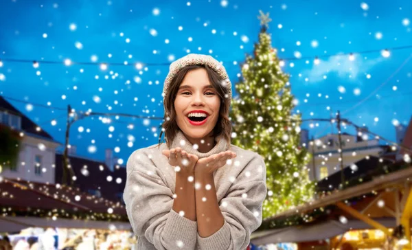 Vrouw in hoed het verzenden van lucht kus op kerstmarkt — Stockfoto
