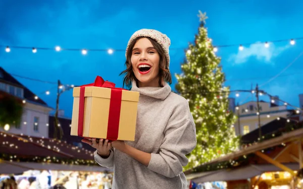 Mujer en sombrero sosteniendo caja de regalo en el mercado de Navidad —  Fotos de Stock