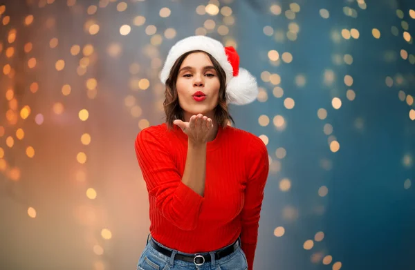 Kobieta w kapeluszu Mikołaja wysyłając pocałunek powietrza na Boże Narodzenie — Zdjęcie stockowe