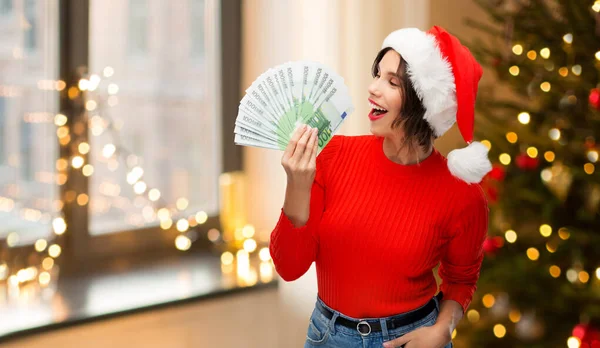 Счастливая женщина в шляпе санта с деньгами на голове — стоковое фото