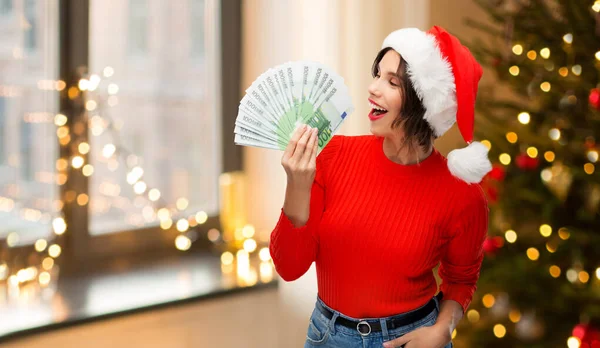 Donna felice in cappello di Babbo Natale con i soldi a Natale — Foto Stock