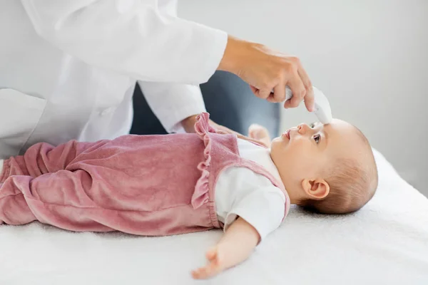 Läkare med termometer mäter barnens temperatur — Stockfoto