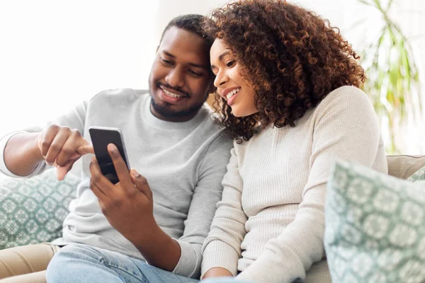 Afrykańska para amerykańska ze smartfonem w domu — Zdjęcie stockowe
