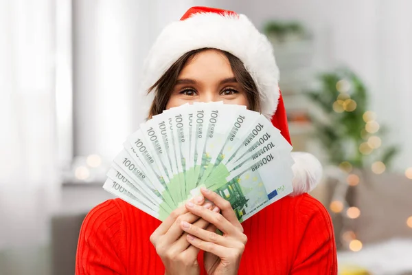 Donna felice in cappello di Babbo Natale con i soldi a Natale — Foto Stock