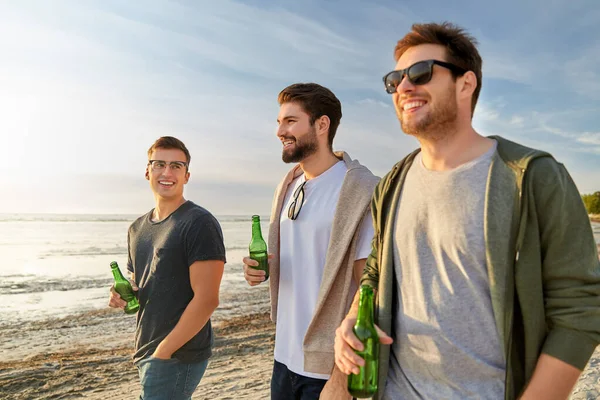 Young men with non alcoholic beer walking on beach — Stock Photo, Image