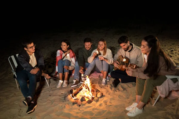 Arkadaşlar sahilde kamp ateşinde marshmallow kızartma — Stok fotoğraf