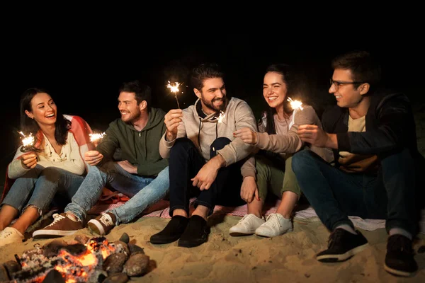 Amis heureux avec des étincelles au feu de camp la nuit — Photo