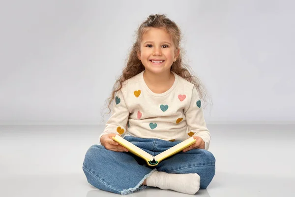 Hermosa chica sonriente leyendo libro en el suelo —  Fotos de Stock