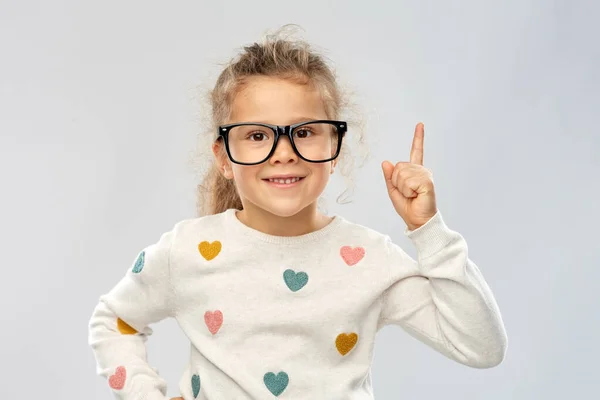 Retrato de menina em óculos apontando dedo para cima — Fotografia de Stock