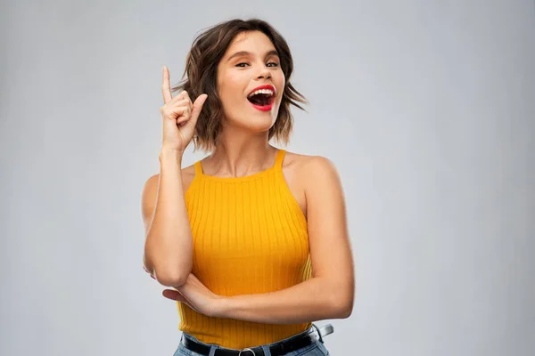 Glücklich lächelnde junge Frau zeigt mit dem Finger nach oben — Stockfoto