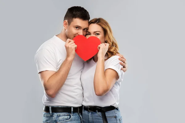 Sonriente pareja escondida detrás de un gran corazón rojo —  Fotos de Stock