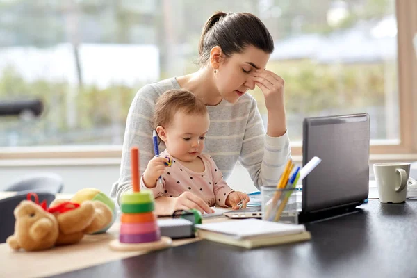 Tired mother with baby working at home office — Stock Photo, Image
