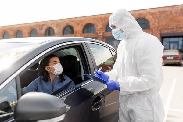 Trabajador sanitario con portapapeles y mujer en coche — Foto de Stock