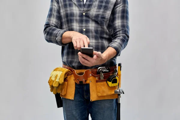 Работник или строитель с телефоном и рабочими инструментами — стоковое фото