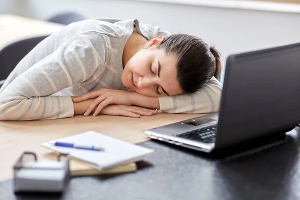 Vermoeide vrouw slapen op tafel met laptop thuis — Stockfoto