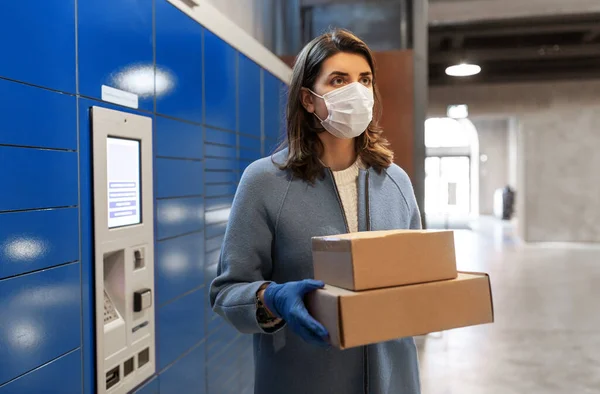 Mujer en máscara con cajas en la máquina de paquetería — Foto de Stock