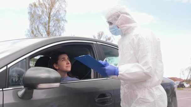 Zdravotnický pracovník se schránkou a žena v autě — Stock video