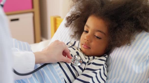 Doctor with stethoscope and sick girl in bed — Stock Video