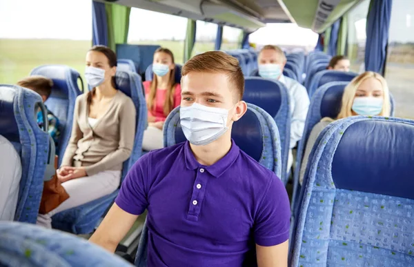 Mladý muž v masce sedí v cestování autobusem nebo vlakem — Stock fotografie