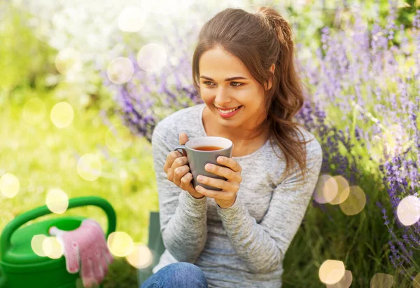 Jonge vrouw die thee drinkt in de zomertuin — Stockfoto