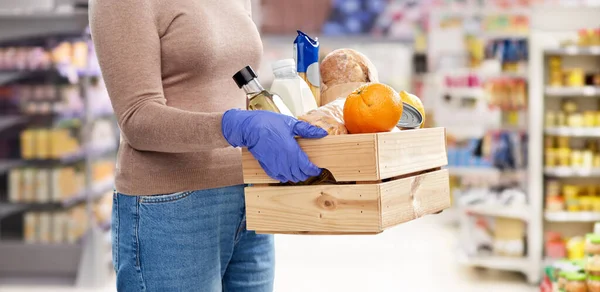 Mujer en guantes con comida en caja de madera — Foto de Stock