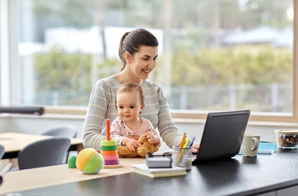 Mãe com bebê e laptop trabalhando no escritório em casa — Fotografia de Stock