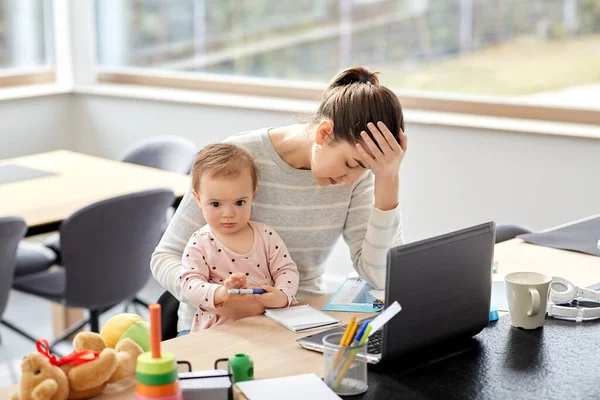 tired mother with baby working at home office