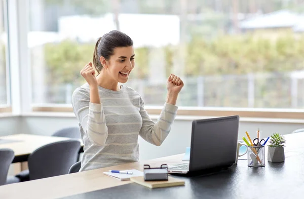 Femme heureuse avec ordinateur portable travaillant au bureau à la maison — Photo