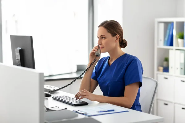 Doctor with computer calling on phone at hospital — Stock Photo, Image