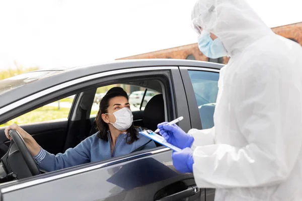 Healthcare worker with clipboard and woman in car — Stock Photo, Image