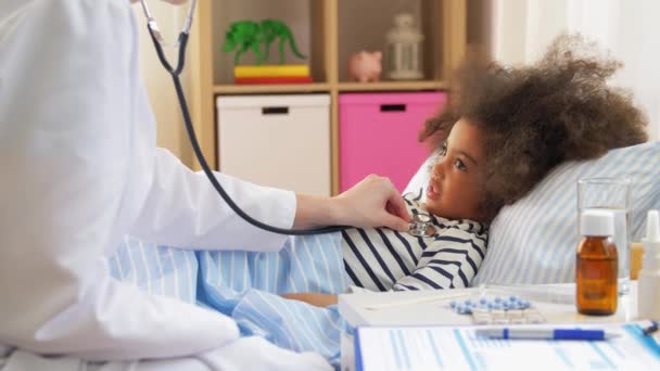 Läkare med stetoskop och sjuk flicka i sängen — Stockvideo