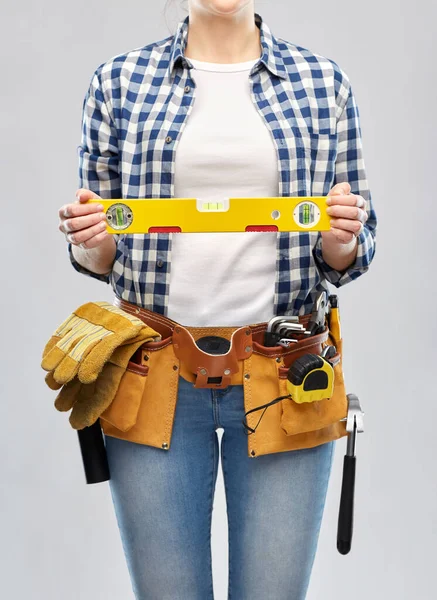 Mulher construtor com nível e ferramentas de trabalho na correia — Fotografia de Stock