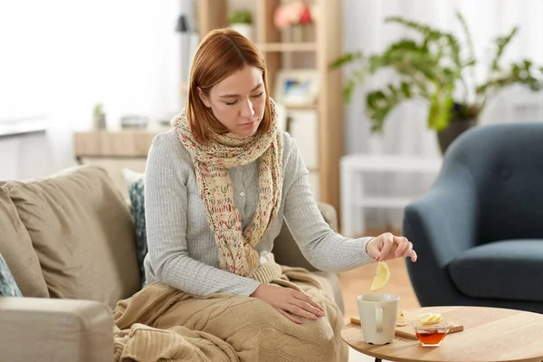 Сумна хвора молода жінка п'є лимонний чай вдома — стокове фото