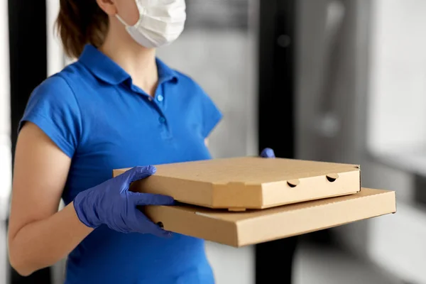 Femme de livraison en masque facial avec boîtes à pizza — Photo