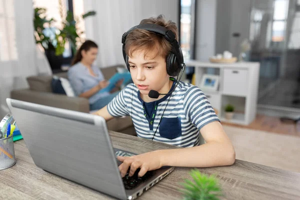 Menino com laptop e fones de ouvido em casa — Fotografia de Stock