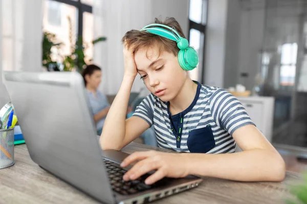 Trieste jongen met laptop en hoofdtelefoon thuis — Stockfoto