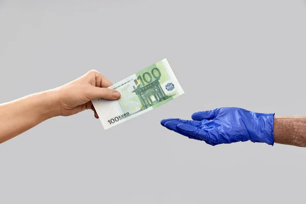 Närbild hand i medicinsk handske ger pengar — Stockfoto