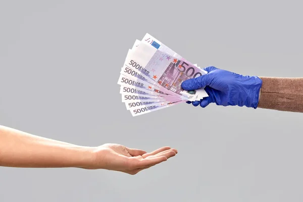 Egyik kéz az orvosi kesztyűben pénzt ad a másiknak. — Stock Fotó