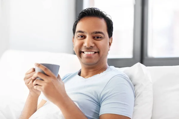 Счастливый индиец пьет кофе в постели дома — стоковое фото